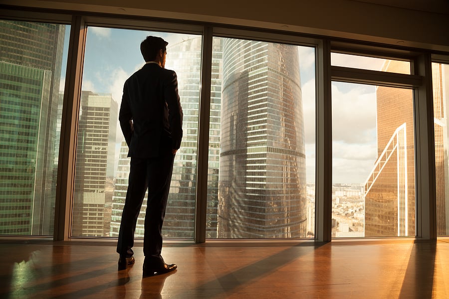 Businessman looking out a high-rise window at the skyline