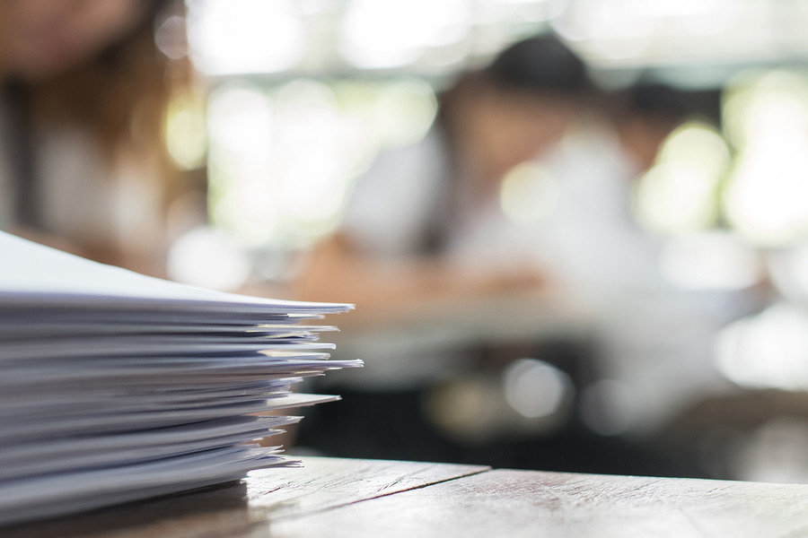 Stack of papers on a table with people blurred in the background