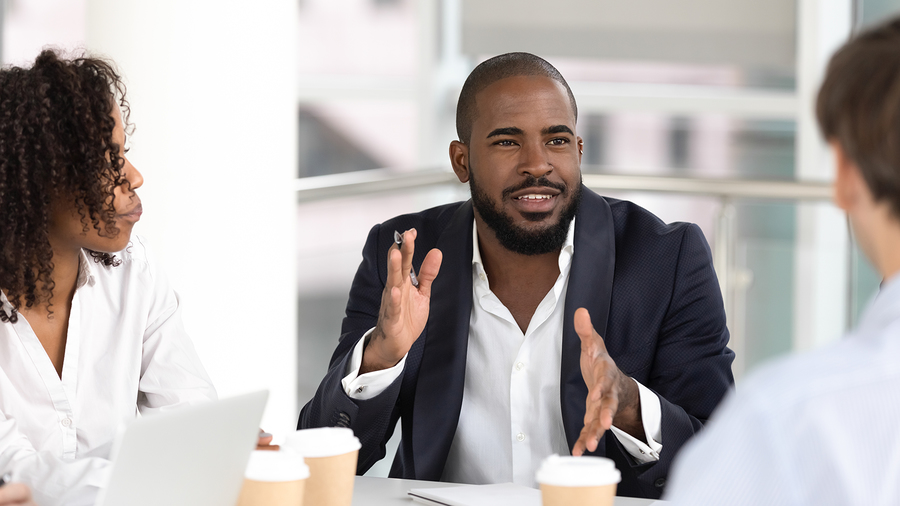 Man gesturing while talking with colleagues at a table