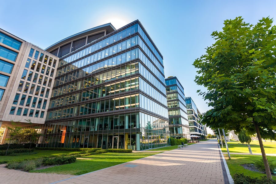 Modern glass office buildings along a landscaped walkway