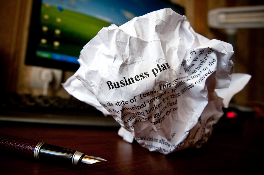 Crumpled business plan document beside a fountain pen