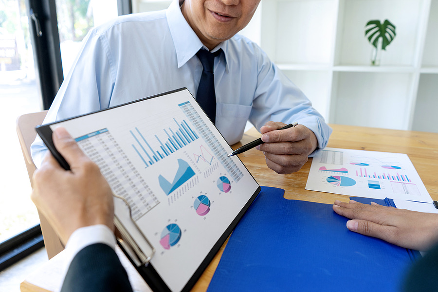 Two professionals reviewing bar and pie charts on a tablet