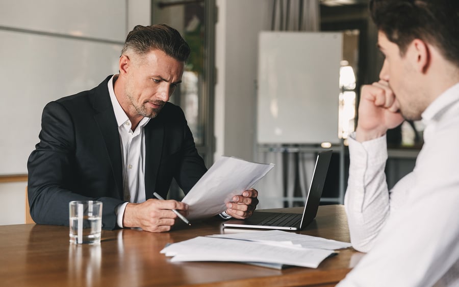 Businessman reviewing documents while a colleague looks on with concern