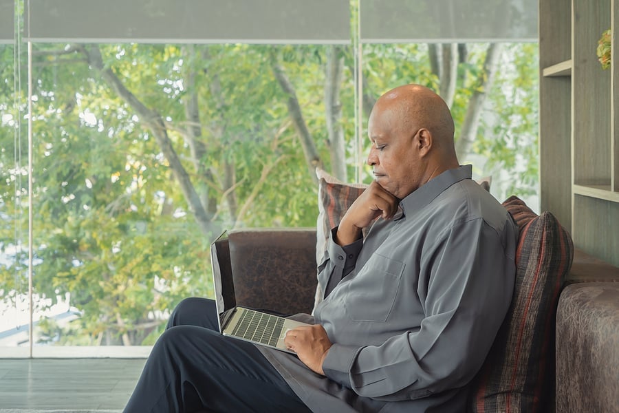 Business owner sitting thoughtfully with a laptop near a window