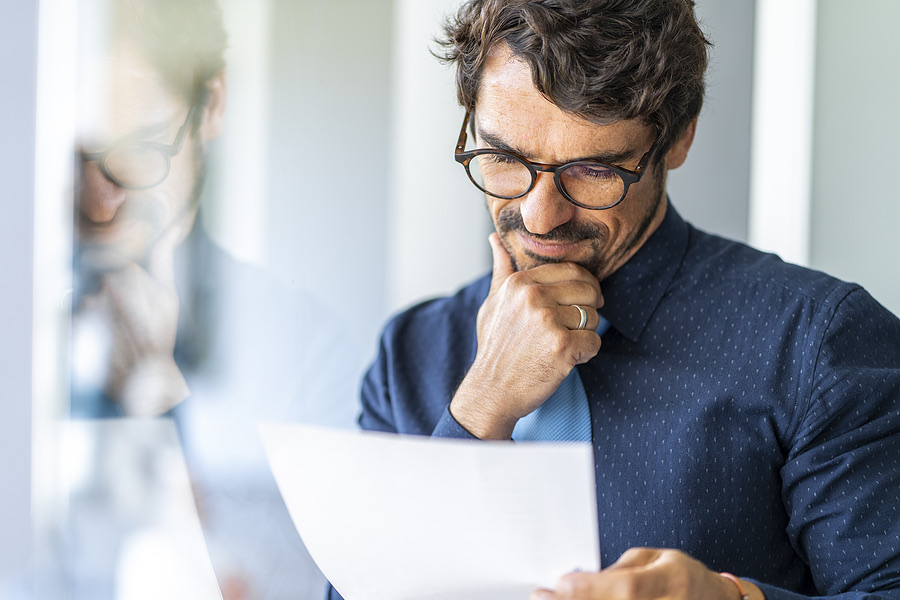 Businessman intently reading a document while wearing glasses
