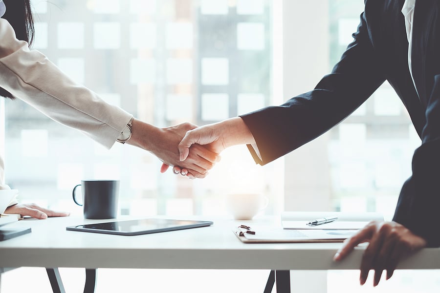 Close-up handshake between colleagues at an office desk