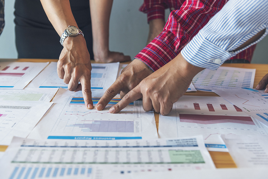 Colleagues pointing to figures on printed reports at a table