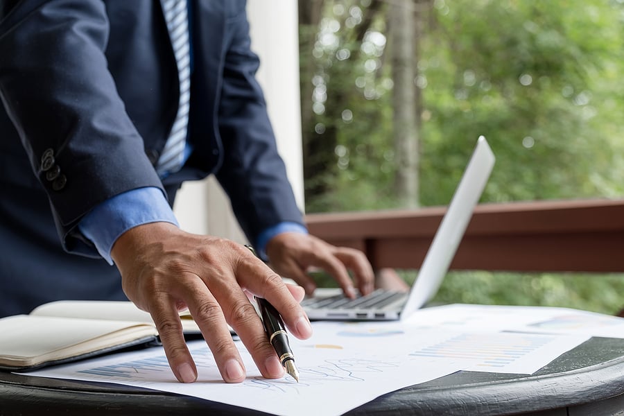 Businessman reviewing a report on a laptop outdoors