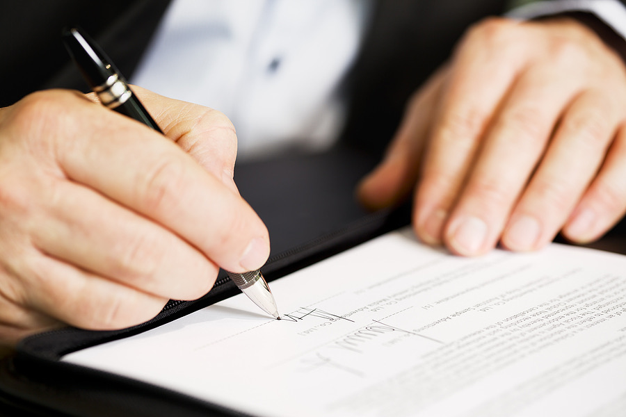 Close-up of a hand signing a business document