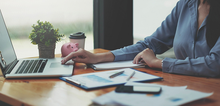 Businesswoman reviewing financial reports beside a piggy bank and coffee