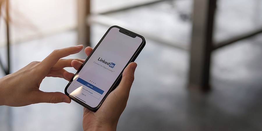 Hand holding a phone displaying the LinkedIn login screen