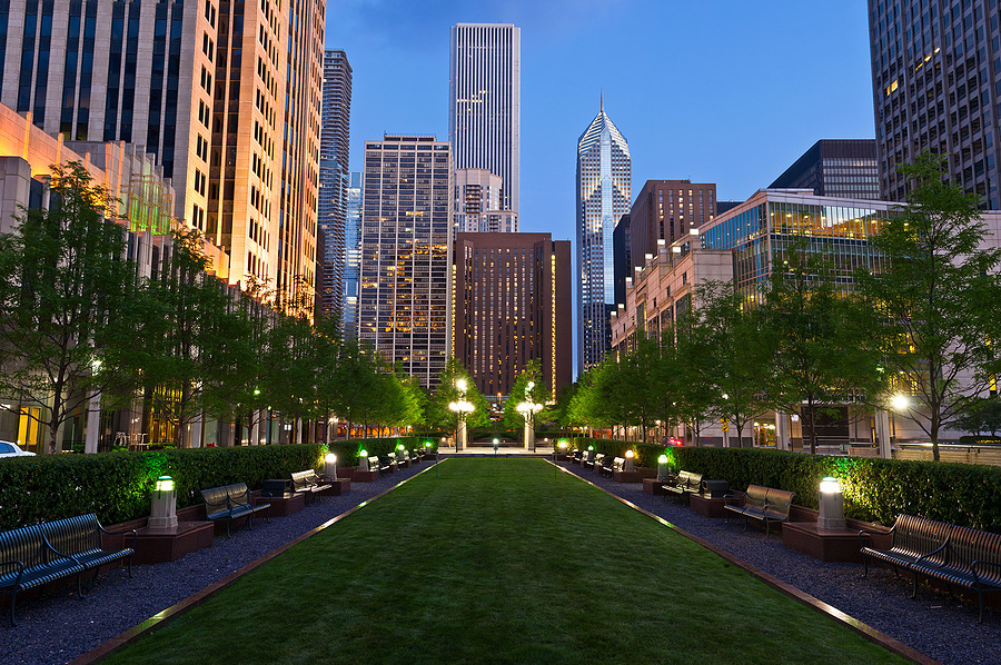 City park pathway lined with trees against an urban skyline at dusk