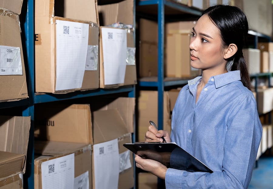 Warehouse worker checking inventory boxes with a clipboard