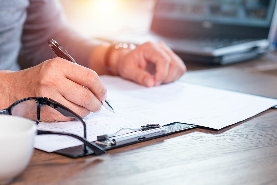Hand writing on a document held on a clipboard