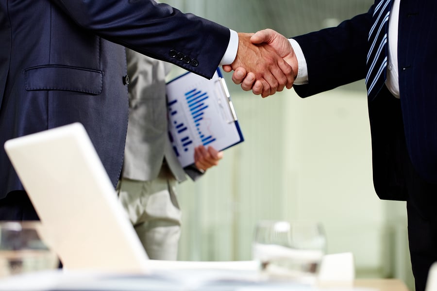 Handshake between two businessmen, one holding a chart
