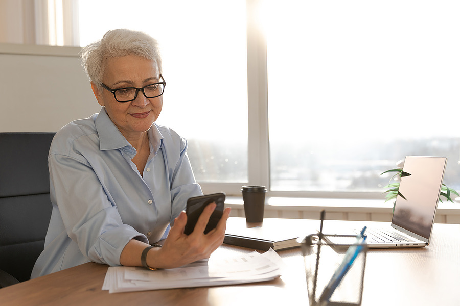 Business owner checking a smartphone at her office desk