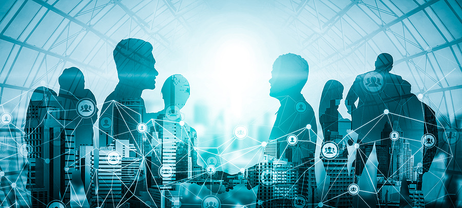Silhouettes of business people connected by a network graphic over a city