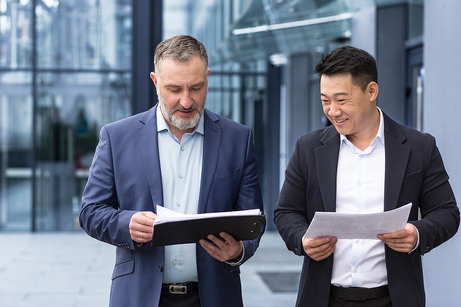 Two colleagues walking through an office building reviewing papers
