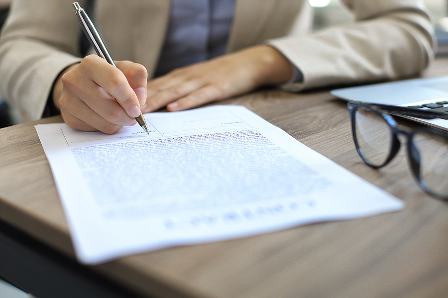Close-up of a hand signing a document at a desk