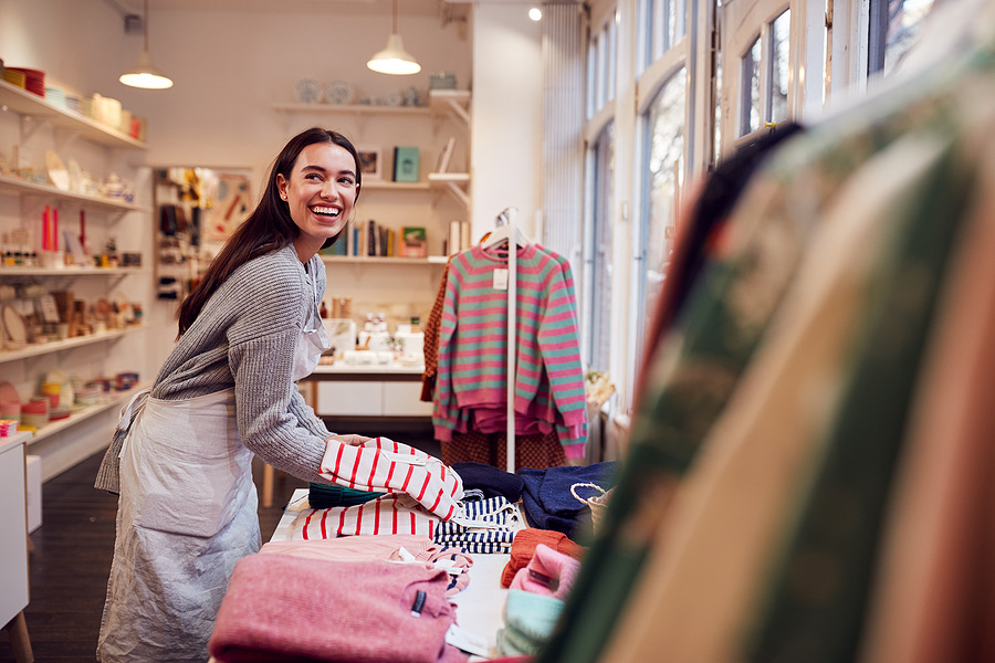 Smiling shop owner arranging merchandise on a display table