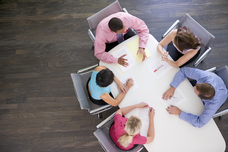 Overhead view of five colleagues seated around a boardroom table
