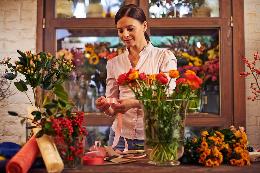Florist arranging fresh flowers at her shop counter