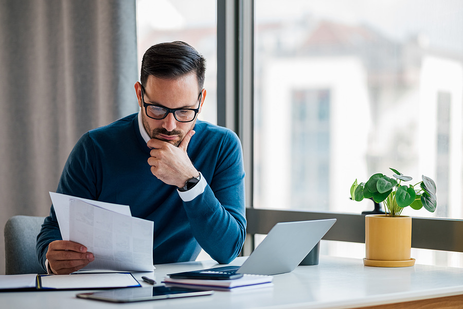 Business owner reading paperwork thoughtfully at a desk