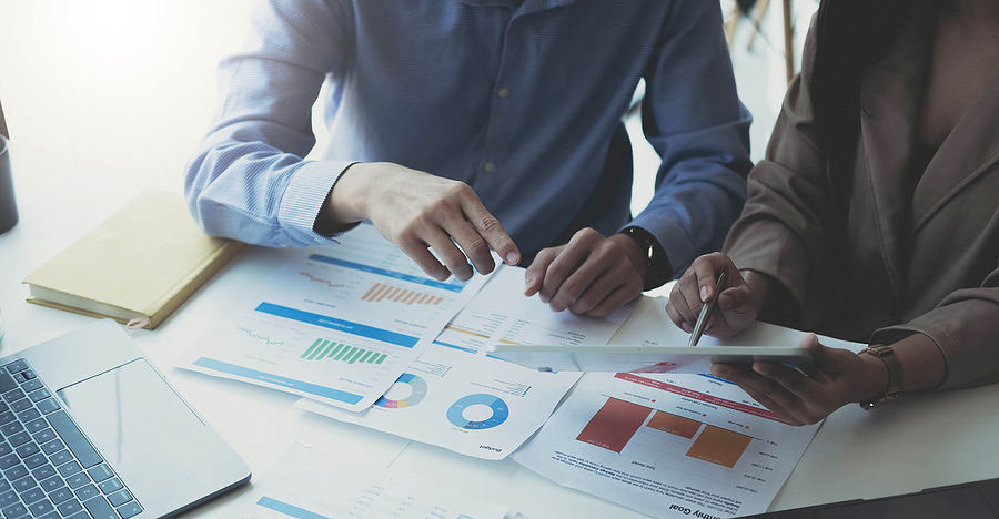 Two colleagues reviewing financial charts on paper at a desk