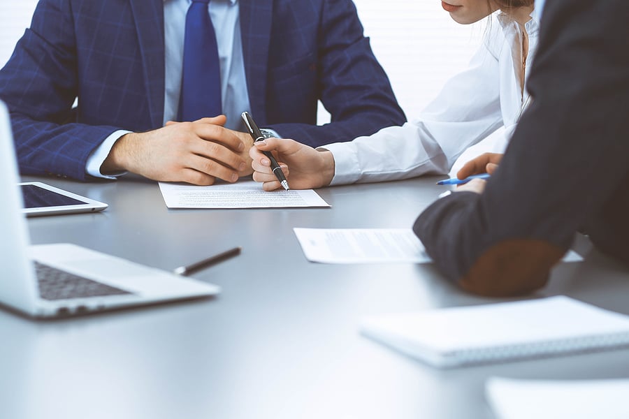 Two people signing a document at a conference table