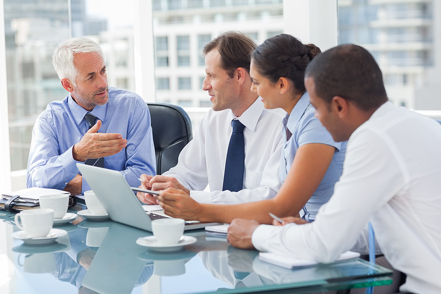 Four colleagues discussing ideas over laptops in a meeting