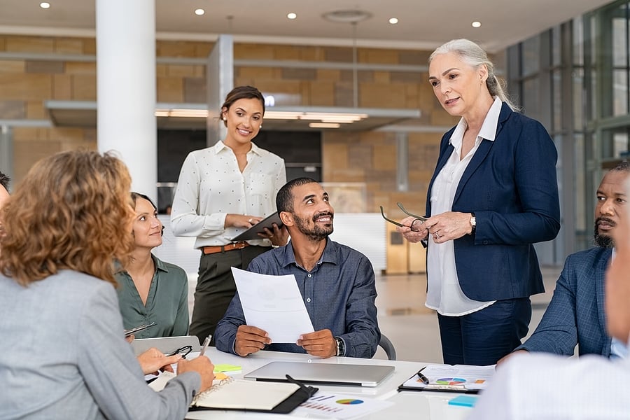Group of colleagues gathered around a manager in an office