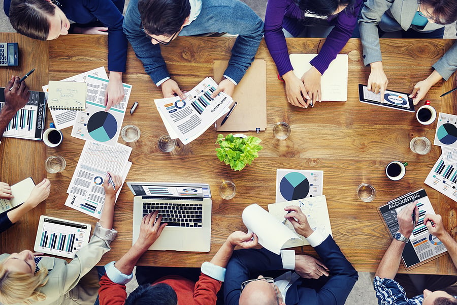 Colleagues reviewing charts and documents around a table from above