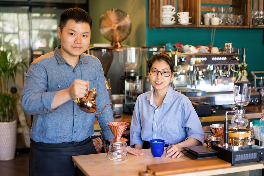 Two cafe owners preparing coffee together at their counter