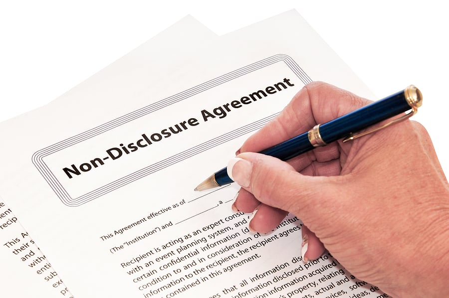 Hand with a pen about to sign a non-disclosure agreement