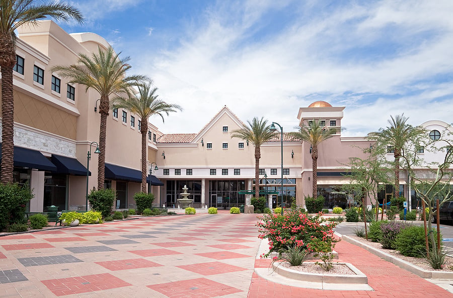 Palm-lined walkway through an outdoor shopping mall plaza
