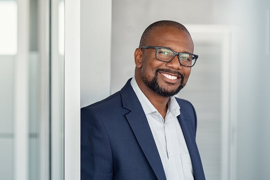 Smiling businessman in a suit jacket posing in an office doorway