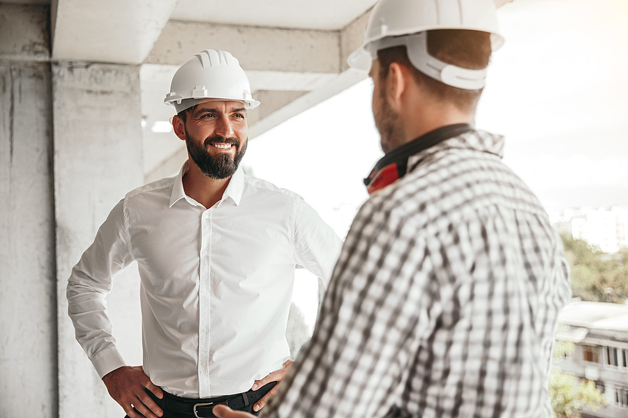 Two contractors in hard hats talking on a construction site