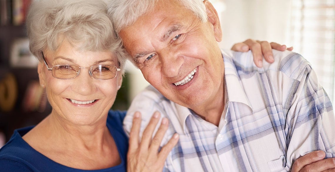Smiling retired couple embracing at home