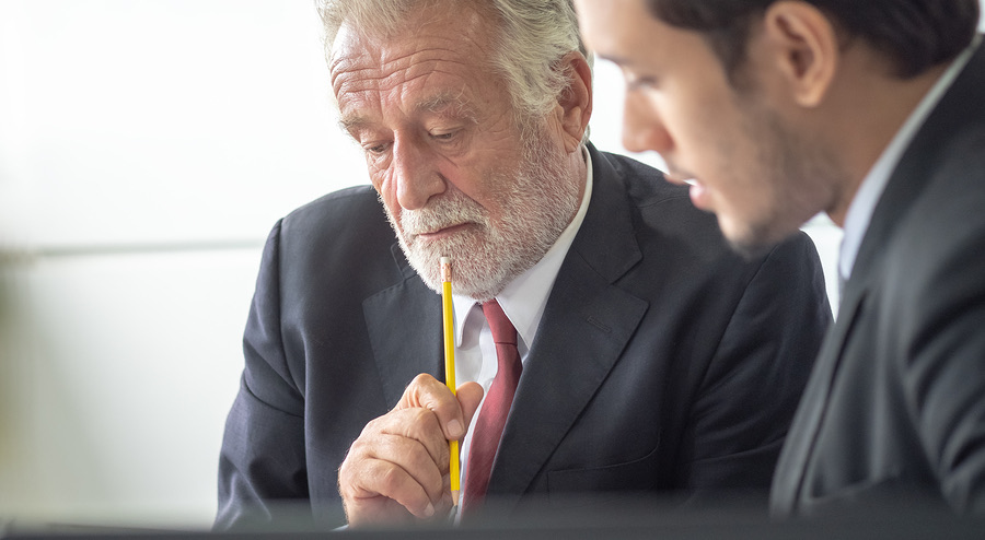 Two businessmen reviewing information closely together
