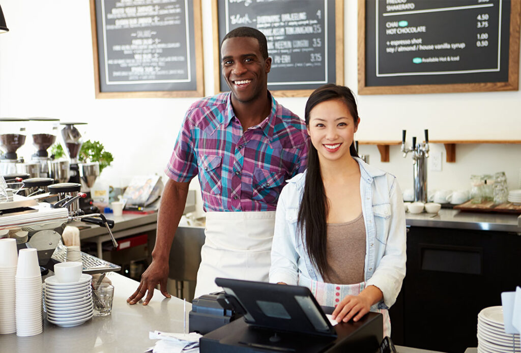 Two coffee shop employees standing behind the counter