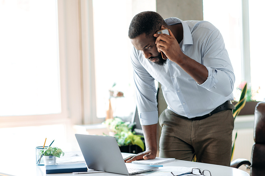 Man on the phone looking concerned while using a laptop