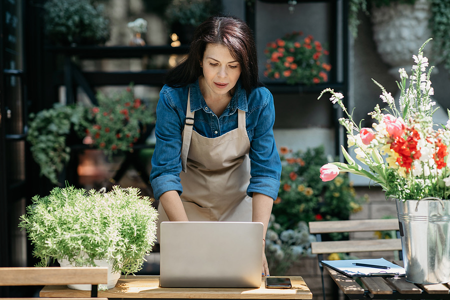 Shop owner working on a laptop at her storefront counter