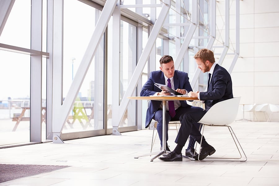 Two businessmen in suits reviewing paperwork together