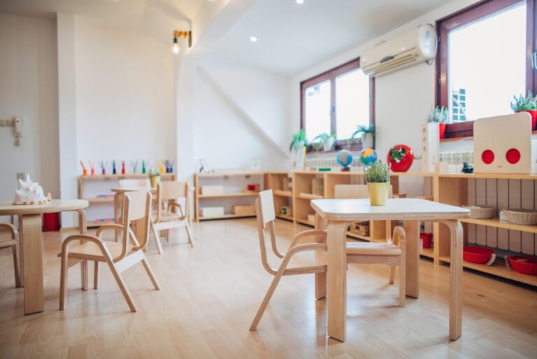 Bright childcare classroom with small tables, chairs, and shelves